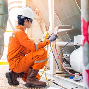 Electrical specialist checking Heating Ventilation and Air Conditioning system (HVAC) for preventive maintenance and while top up refrigerant to the cooling systems.